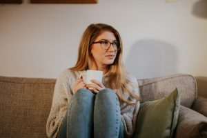 woman on sofa with cup of tea thinking